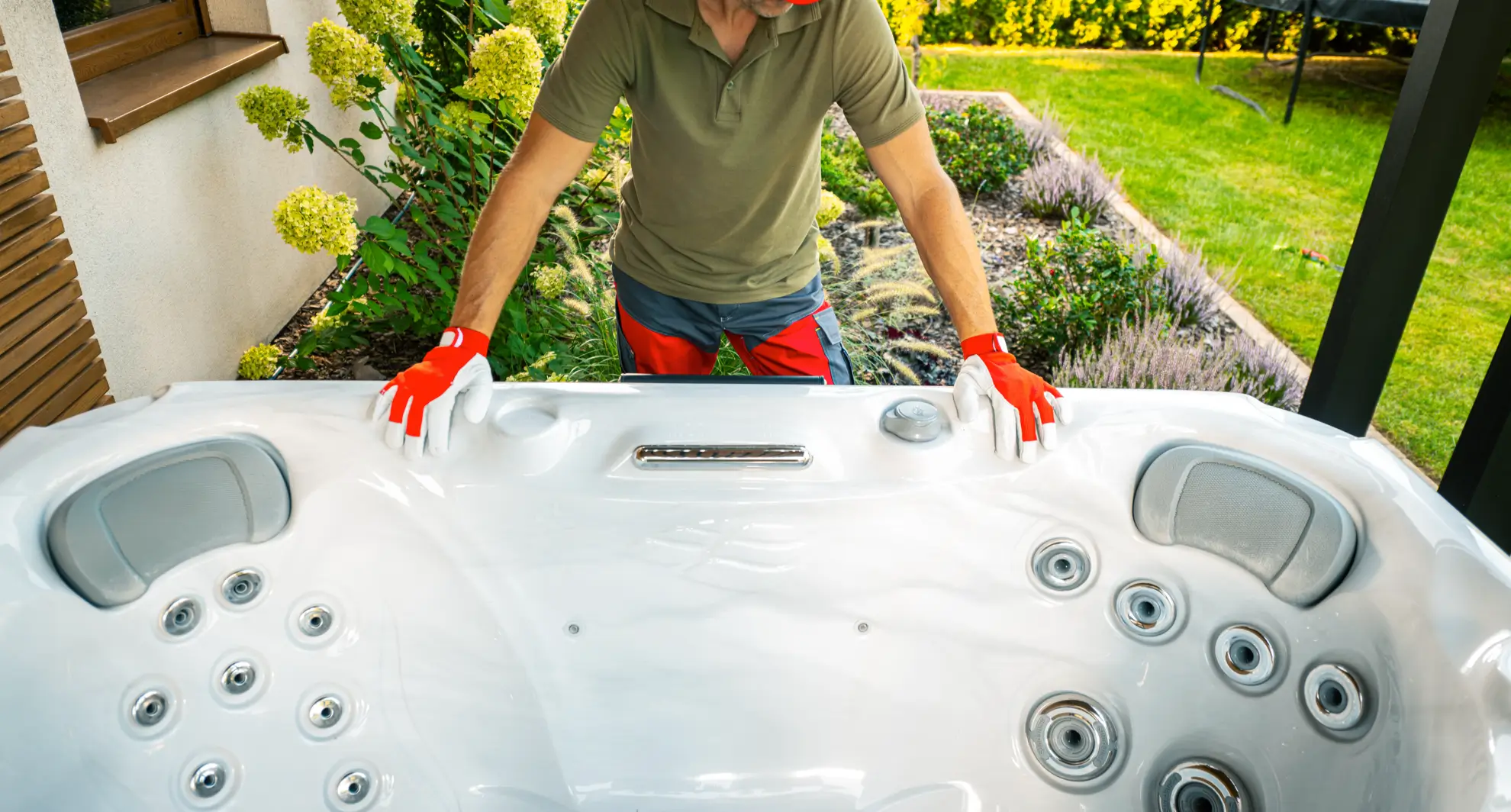 Man in work gloves positioning a hot tub.