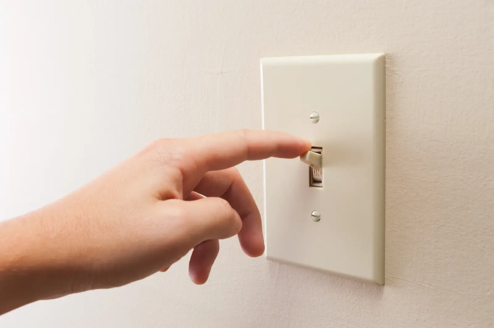 A hand flipping a light switch