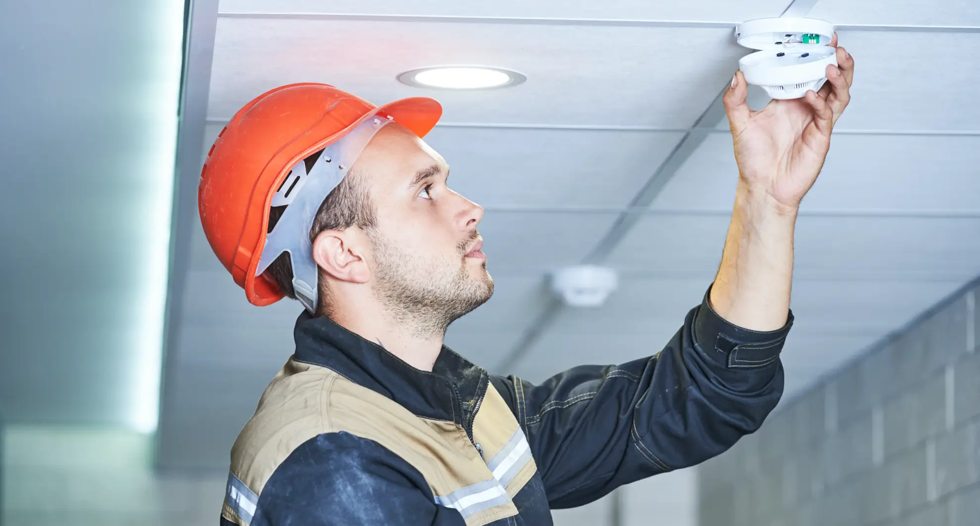 An electrician replacing hardwired smoke detectors.