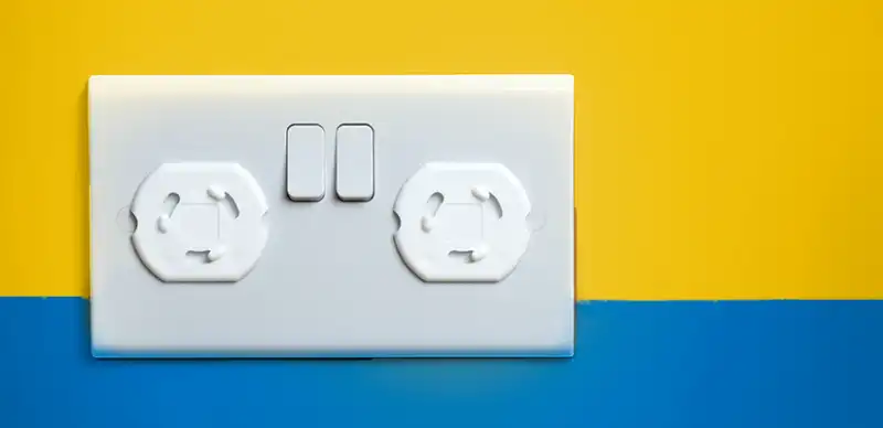 Outlet with outlet covers on a wall painted half yellow and half blue.