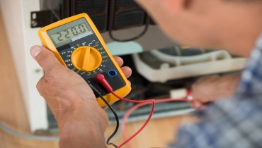 Man checking a refrigerator with a digital multimeter