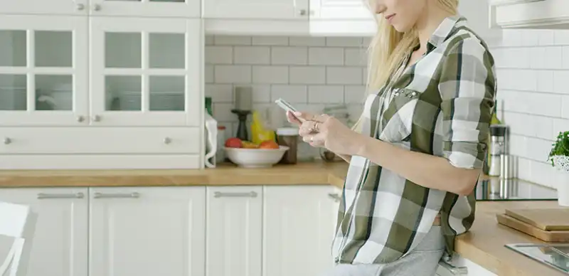 Woman on her smartphone in a kitchen.