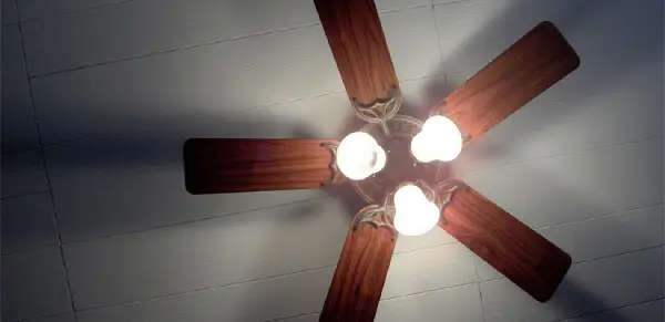 A wooden ceiling fan with three light bulbs in the center of it.